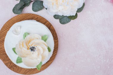 cream cake with a large flower on a pink background top view