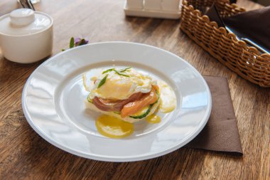 sandwich for breakfast with poached egg and low salt fish with cream sauce on the table