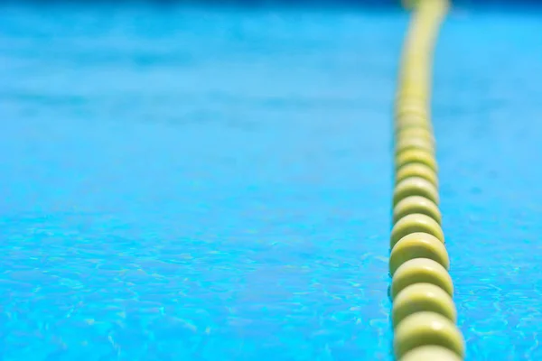 Sarı göstergeyi kayan nokta çizgi ile şeffaf su Yüzme Havuzu. Yaz güneşi parlaklığı ile yoğun mavi. Serin banyo almaya hazır