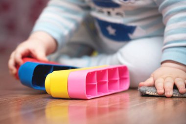 Little boy is playing with toys on the floor.