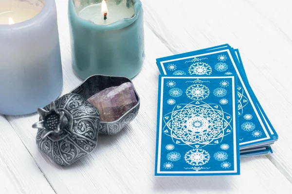 Blue tarot cards and burning candle on white table background.