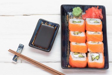 Suşi Philadelphia 'yı beyaz ahşap masa arkasında yuvarlıyor..