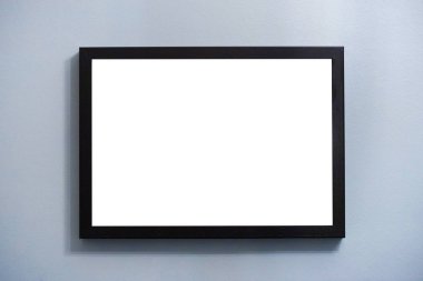 Mavi duvarda asılı olan boş fotoğraf çerçevesi.