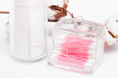 Beyaz arka plandaki kabın içinde pamuk ve kulak çubukları.