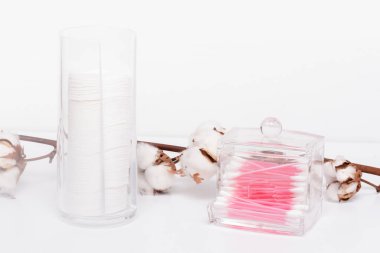 Beyaz arka plandaki kabın içinde pamuk ve kulak çubukları.