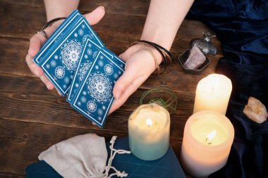 Kahverengi masa arkasında elinde tarot kartları olan falcı..