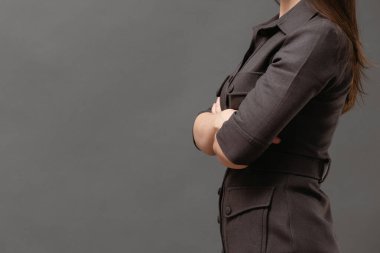 Sert kadın patron ellerini çapraz tutuyor. Gri arka plana yakın..