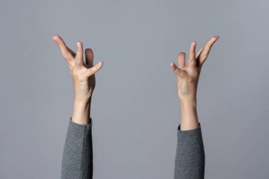 Gri arka planda elini kaldırmış bir kadın..