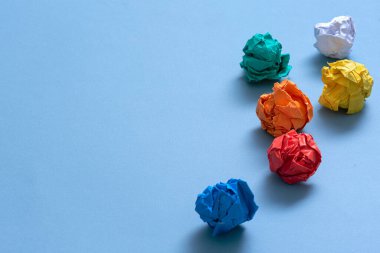 Mavi arkaplan üzerine buruşuk renkli kağıt sayfaları.