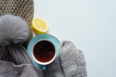 Bir fincan sıcak çay, limon ve kalın giysiler gri düz arka planda fotokopi alanı ile uzanır..