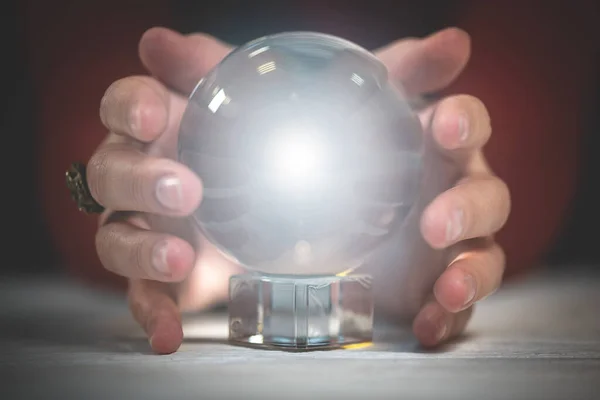 Crystal ball with mystic light within and fortune teller hands.
