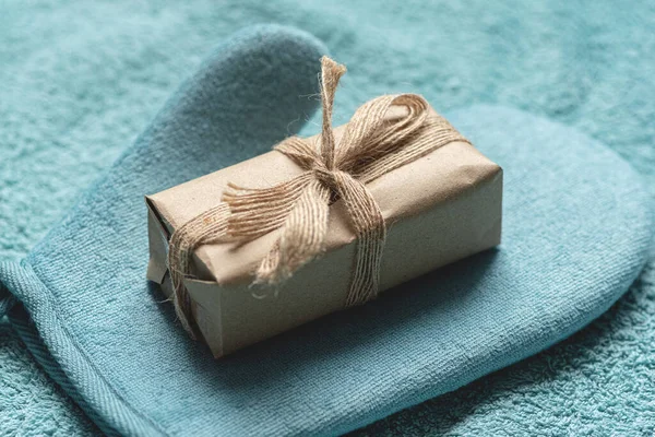 Bath towel, wash glove and craft soap in paper package close up. Hygiene abstract background.