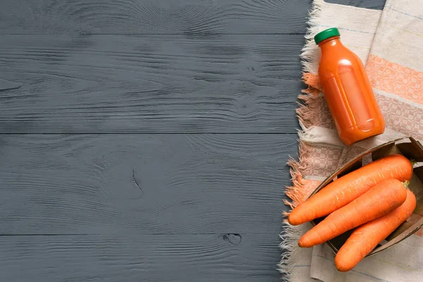 Carrot juice in a bottle on gray wooden table flat lay background.