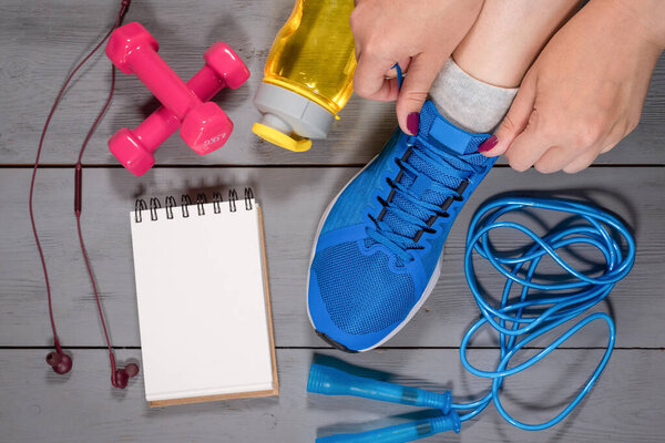 Макет тренировочного списка. Блокнот, кроссовки, скакалка и гантели на полу
.