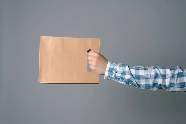 灰色の背景に隔離された男性の手の中の紙のショッピングバッグ — ストック写真