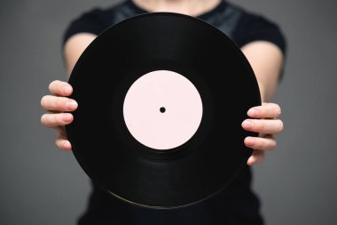 Gri arka planda şarkıcı elinde vinil bir plak..