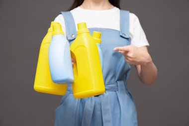 Gri arka planda deterjan şişesi olan kadın. Yakın plan..