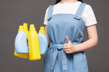 Gri arka planda deterjan şişesi olan kadın. Yakın plan..