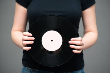 Gri arka planda şarkıcı elinde vinil bir plak..