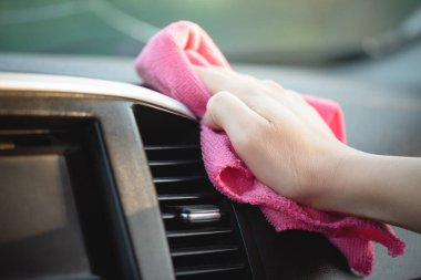 Temizlikçi, arabanın ön panelini bir paçavrayla silip parlatıyor..