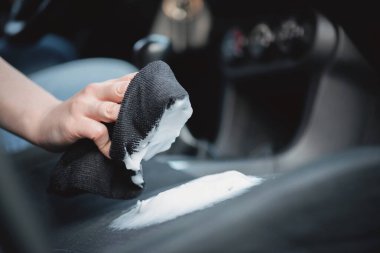 Temizlikçi araba koltuklarını köpük temizleyiciyle temizliyor..