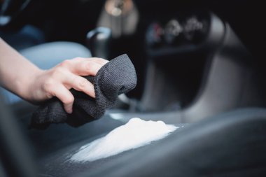 Temizlikçi araba koltuklarını köpük temizleyiciyle temizliyor..