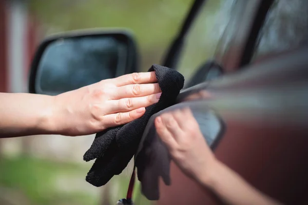 Cleaner is cleaning a car exterior with a rag close up.