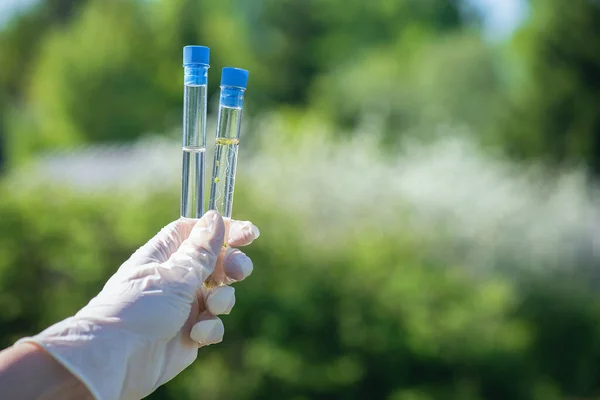 Bilim adamı ellerinin arasında temiz ve kirli bir su test tüpü tutuyor..