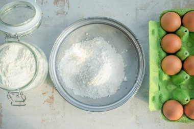 Elekte bir un ve beyaz mutfak masasında taze yumurtalar düz arka planda yatıyordu..