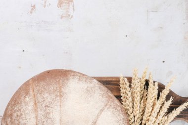 Taze ekmek ve buğday kökleri kırsal beyaz masa düz zemin üzerinde fotokopi alanı ile kesim tahtasında yatıyordu.