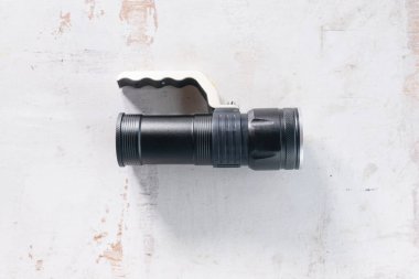 Eski beyaz ahşap arka planda sapı olan modern siyah el feneri..