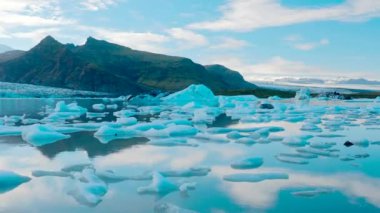 Buzdağlarının ve Jokulsarlon 'un üzerinde gün batımının zamanlaması, İzlanda' daki bir buzul gölü. Arka planda karlı dağlar. Temiz buzlu su. İzlanda buzulu. Mavi renk. 