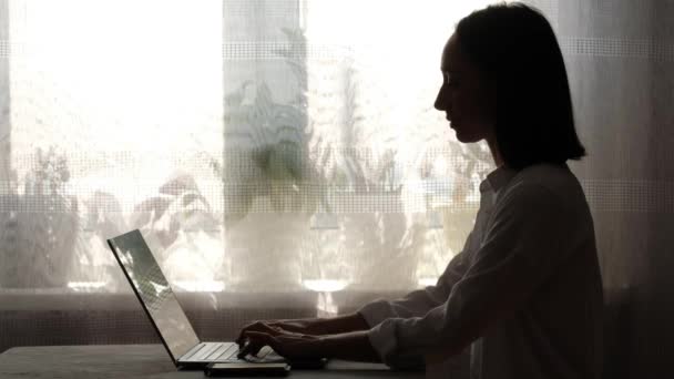 Chica trabajando en casa e impresiones en un ordenador portátil . — Vídeo de stock