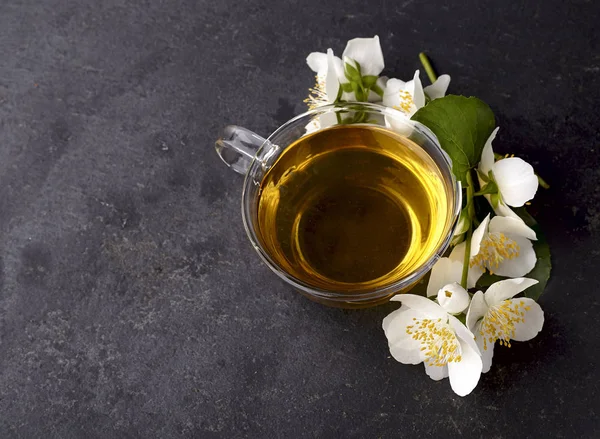 En kopp grönt te och Jasmine blommor på en svart bakgrund. Ört — Stockfoto