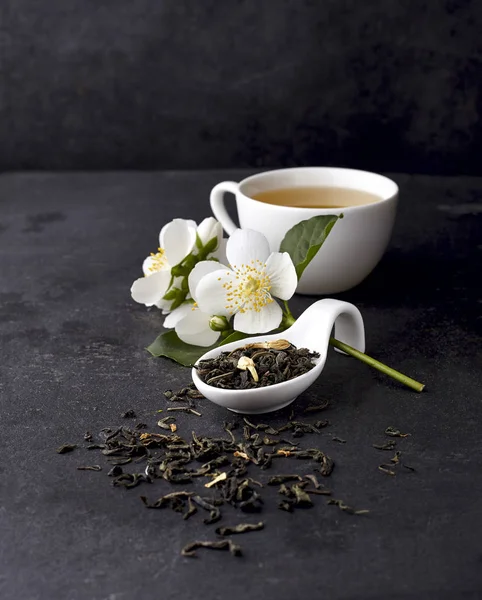 Jasmin blommor och kopp friskt te på en svart bakgrund. H — Stockfoto