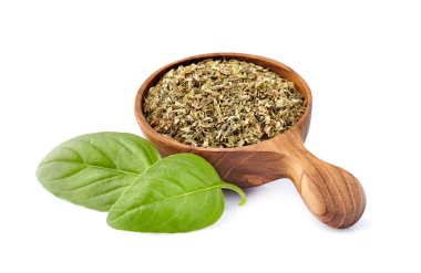 Tahta kaşıkta kuru fesleğenli taze fesleğen yaprakları beyaz arka planda izole edilmiş..