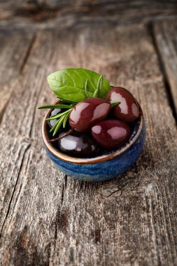 Ahşap arka planda fesleğenli ve biberiyeli zeytin..