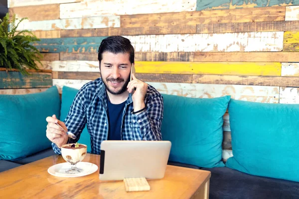 Framgångsrik modern medelålders man frilansare talar på telefon i café medan du använder digital tablett och njuta av dessert i trendiga café - fjärrarbete — Stockfoto