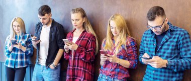 Üniversite duvarında izole edilmiş akıllı telefonları kullanan gençler eğleniyor.