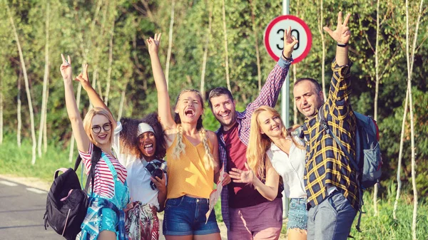 Group of best friends having fun taking selfie with raised arms during travel adventure in countryside