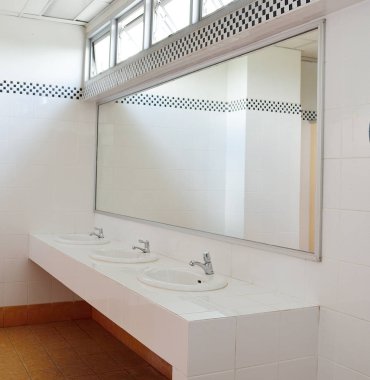 Bathroom at office.Handbasin and mirror in toilet clipart