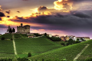 The sky of Grinzane Cavour - A spectacular sunset sky overhangs the village of Grinzane Cavour with its castle (Unesco World Heritage Site) surrounded by vineyards in the Langhe, Piedmont, Italy.  clipart