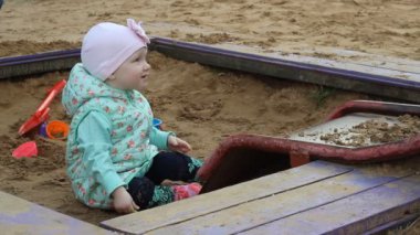 Küçük kız bir kürek kum ile oynamak