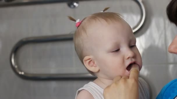 Madre limpia sus pequeños dientes hijas, primer plano — Vídeo de stock