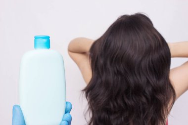 Bottle with shampoo on the background of a girl with lush beautiful hair, copy space clipart