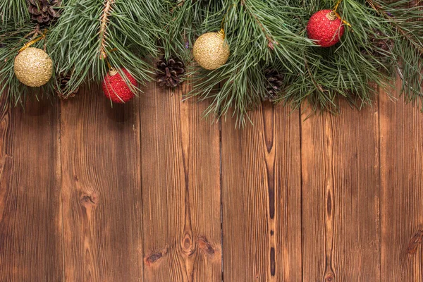 Grüne Tannenzweige, die mit bunten Kugeln auf einem hölzernen Hintergrund dekoriert sind. Platz für Text, Kopierraum, Weihnachten — Stockfoto