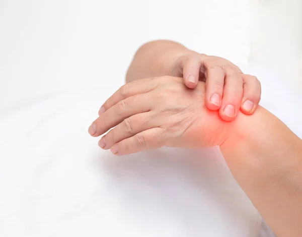 Woman holds on wrist joint on a white background. The concept of pain and inflammation of the wrist joint, tunnel syndrome and arthritis, copy space — Stock Photo, Image