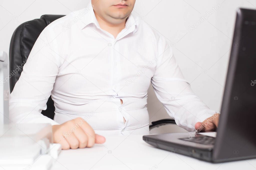 Male office worker with double chin and obesity at a laptop. The concept of malnutrition and sedentary lifestyles