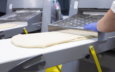 Kadın aşçı pizza ve puf yapmak için hamuru hamurun üzerine sarar.