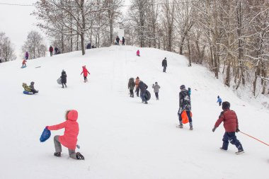 Birçok insan kışın karda bir kızağa biner, çocuklar ve yetişkinler. Bobruisk, Belarus - 03.01.19